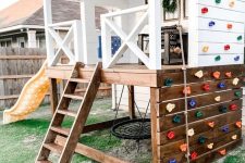 06 a color block kids’ playhouse outdoors, with a stained chair, a ladder, some decor and a colorful climbing wall