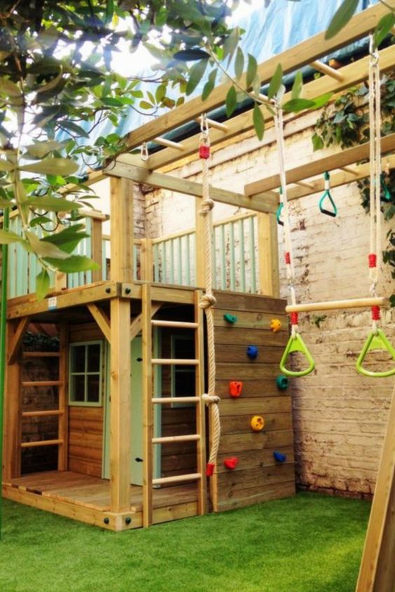 a fun and colorful backyard with a climbing wall, a swing, a little playhouse with a ladder and some windows