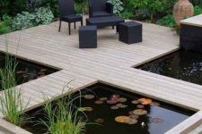 28 a modern garden with green lawn and some blooms, a wooden deck with black outdoor furniture, a couple of ponds