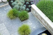 34 a modern outdoor space with lots of grasses and plants, with stone pavemets and a small water feature with a large rock