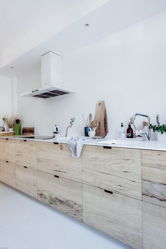 a Nordic neutral kitchen with no hardware cabinets, a white stone countertop, a white hood and neutral fixtures