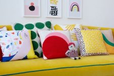 a bold gallery wall with abstract prints in various colors adds interest to the bright couch zone