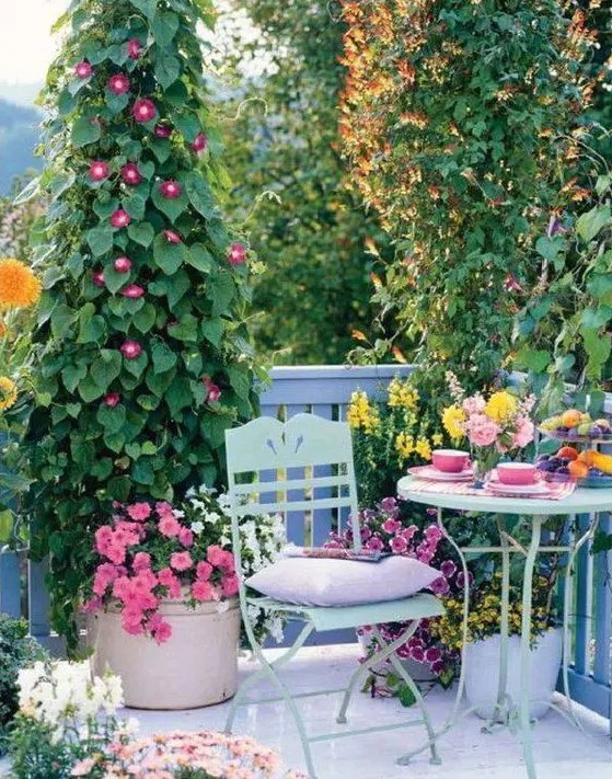a bright spring terrace with elegant vintage furniture of metal, pastel pillows, bold potted blooms and greenery