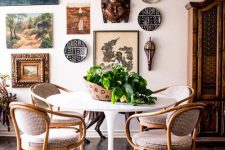 a catchy dining room with a round table and vintage chairs, a rug, a free form gallery wall and a cool chandelier