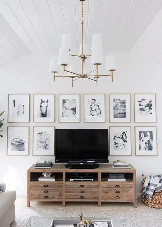 A chic gallery wall with thin gold frames, white matting and black and white photos framing the TV is cool