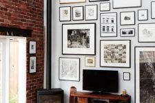 a cool gallery wall done with matching neutral and black frames of various sizes and with prints is a stylish idea