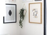 a cool modern gallery wall with mismatching white, black and neutral frames and various types of art plus hanging greenery