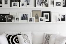 a large Scandinavian gallery wlal with white ledges, black and white artworks in various black and white frames