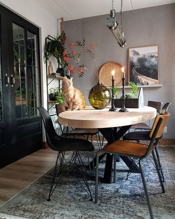 A lovely Scandinavian dining room with a taupe accent wall, a light stained oval table, mismatching chairs and open shelving