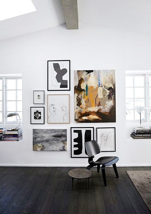 A lovely modern gallery wall with a non framed central artwork and thin framed other works is chic