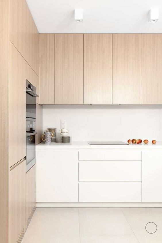 A minimalist kitchen with light stained and white cabinets, built in appliances and white countertops is a lovely space to be in
