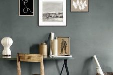 a moody gallery wall with thin blonde wood and black frames and black and white artworks for a modern space