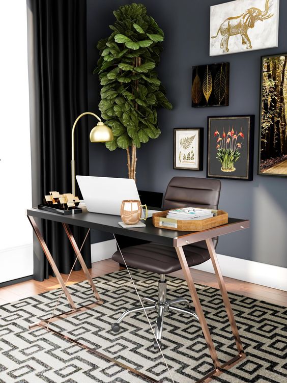 a moody home office with black walls, a brown desk and a chair, a geo printed rug, a lovely gallery wall and a potted tree