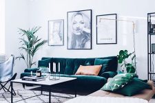 a serene Scandinavian living room with a dark green sofa, a beige leather daybed, a blakc leather chair, a coffee table and a black and white mini gallery wall