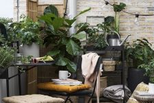 a small boho terrace with metal furniture, a wooden table, potted greenery, lights and a wooden screen