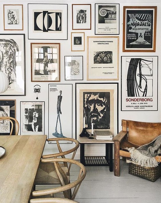 A stunning gallery wall with thin black and brown frames and black and white artworks is a bold eye catcher