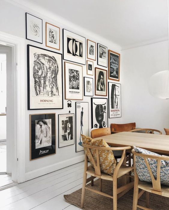A stylish Scandinavian dining room with a light stained table and matching chairs, a statement black and white gallery wall