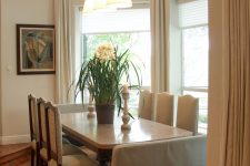 21 a neutral dining room with tall windows with arched tops and neutral curtains that cover the windows partly
