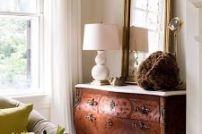 a beautiful ornate stained sideboard with a white stone countertop, a large mirror and a chic table lamp are a great combo for a living room