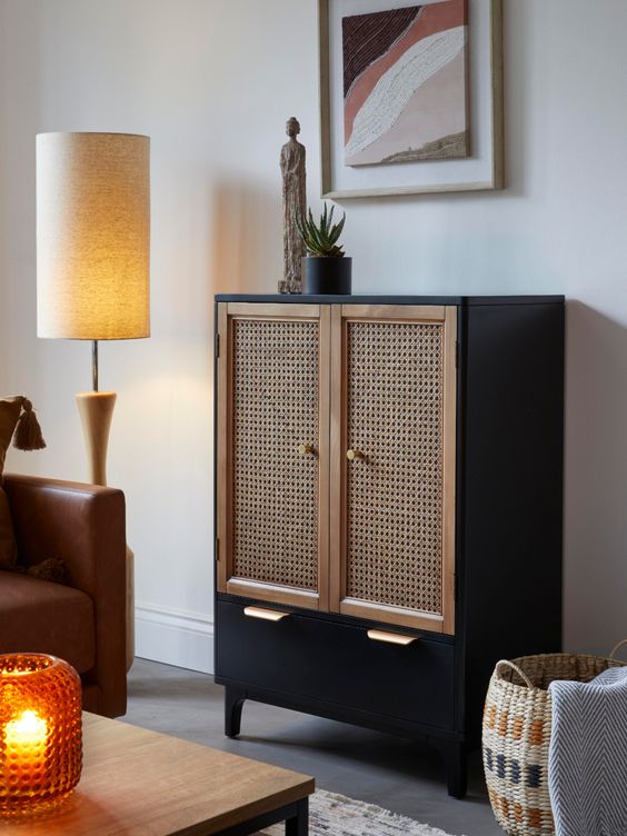 A black cabinet with a large drawer and cane webbing doors is an elegant and timeless solution for a boho or mid century modern space and it looks very contrasting