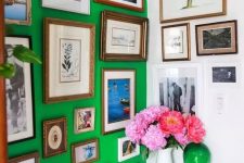 a bold and catchy bathroom with a green accent wall, a colorful gallery wall, white appliances and bold blooms