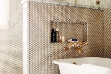 a chic bathroom with grey tiles and penny ones on the walls, a pony wall, brass touches and a vintage bathtub