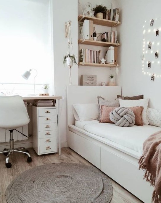 A chic neutral teen room with wall mounted shelves, a comfy white bed with lots of pillows, a desk and a white chair plus potted plants