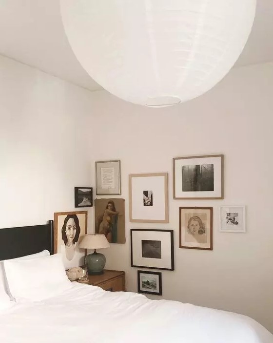 A neutral bedroom with a vintage feel, a black bed with white bedding, a vintage inspired corner gallery wall is amazing