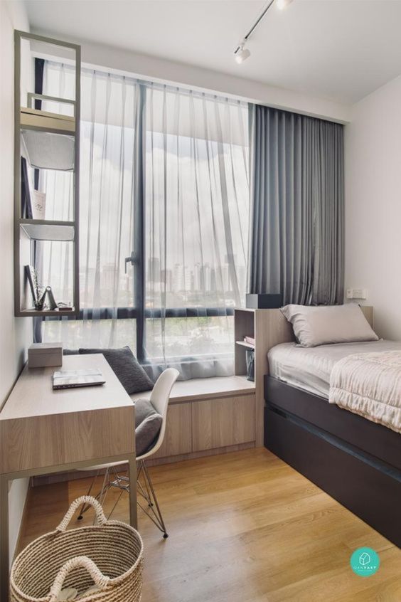 A neutral welcoming teen bedroom with a windowsill seat, a desk and a chair, a bed with storage drawers and a wall mounted shelf