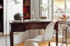 a refined contemporary home office with built-in bookshelves, a vintage stained desk, a white sculptural chair and a small table
