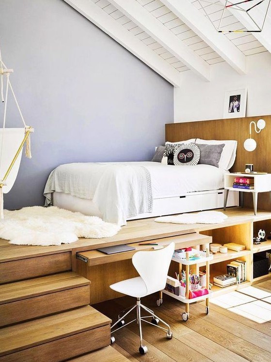 A teen room with a raised platform bed, a built in desk and storage compartments, a white chair and a suspended chair