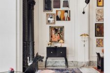 a whimsical interior with a bright gallery wall, a black vintage dresser, glass tables and rust chairs is a beautiful space