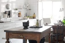 a white Scandinavian kitchen with white square tiles on the walls, a vintage stained kitchen island and a table in one, pendant lamps