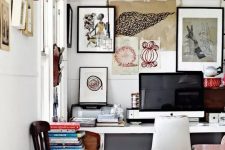 an eclectic home office wiht a white desk and a creamy chair, with a messy gallery wall that extends to the next wall, some chairs and a bold rug