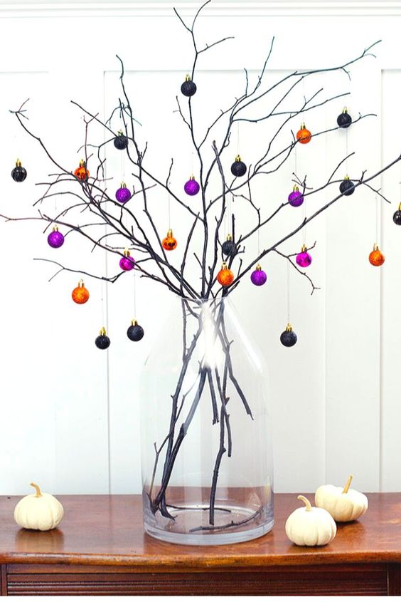 A branch Halloween tree with mini black, orange and purple ornaments   just buy some pretty colorful ones and create a tree
