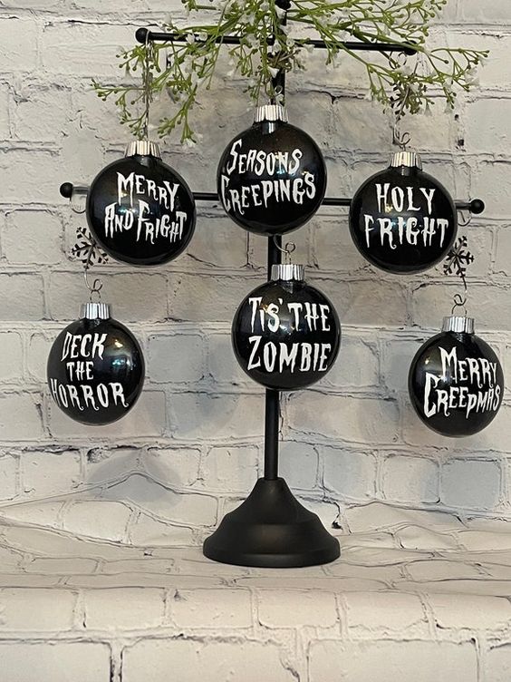 A metal Halloween tree with greenery and black ornaments with white letters   you can DIY some for your tree