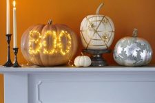 20 a lovely modern pumpkin arrangement of a pumpkin with lights, a white pumpkin with gold spiders and spider web, a grey pumpkin with silver leaves