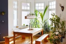 a bay window featuring a dining set with benches and lots of potted plants all over is a very cozy space flooded with light