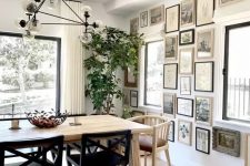 a beautiful dining room with a light-stained table and mismatching chairs, a chic chandlier and a monochromatic gallery wall