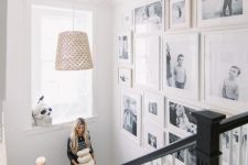 a free form gallery wall with black and white family pics and white frames is a very chic and stylish idea for any space