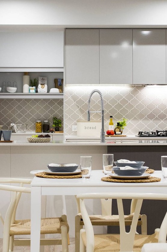 a grey and white contemporary kitchen with a grey arabesque tile backsplash, built-in lights and open storage shelves