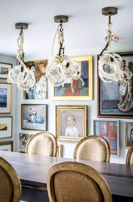A jaw dropping dining room with a simple table and vintage chairs, whimsical rope pendant lamps and artworks all over the space