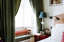 a refined vintage bedroom with a small bay window done with a sitting space, pillows and a cushion, green curtains