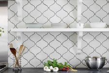 a stylish black and white kitchen, with black countertops and a creative white arabesque tile backsplash is a lovely and chic idea