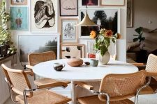a stylish mid-century modern dining room with a round stone table, cane chairs, a lovely gallery wall and a pendant lamp