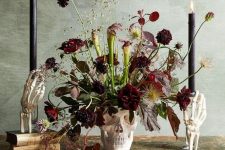 07 a skull vase with burgundy blooms, dark and usual leaves, greenery and black candles for Halloween