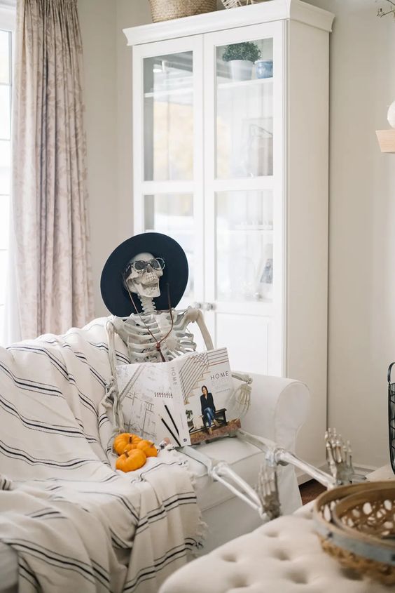 Halloween decor with a skeleton reading a book in a hat and some pumpkins will be a great idea for your party