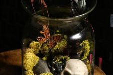 12 a Halloween terrarium with moss, pebbles, butterflies, dried blooms and a small skull is a bold and cool idea for Halloween decor