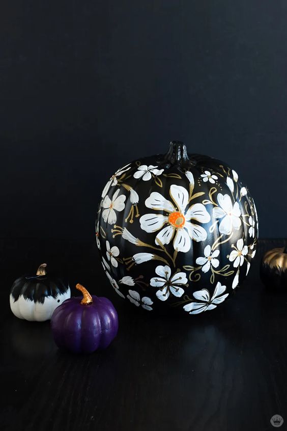 Elegant Halloween pumpkins   a black one with gorgeous white blooms painted, a black and white and a purple one