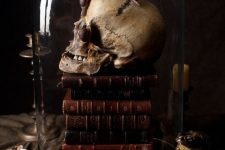 14 vintage Halloween decor of a stack of vintage books, a skull covered with snails, a cloche is a stunning moody solution